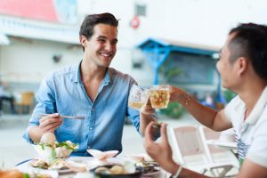 Two men sitting in a restaurant eating and laughing